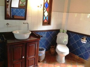 Un baño con lavamanos blanco, gabinete de madera, paredes con azulejos azules y un inodoro blanco.
