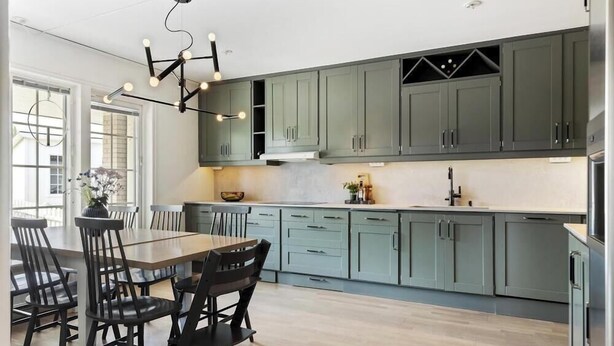 A modern kitchen with grey cabinets, a dining table with chairs, and pendant lighting.