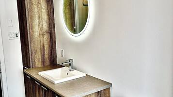 Une salle de bain avec un meuble-lavabo en bois, un lavabo blanc et des toilettes.