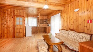 En inredning med träpanel, en soffa, ett bord och ett litet kök.
