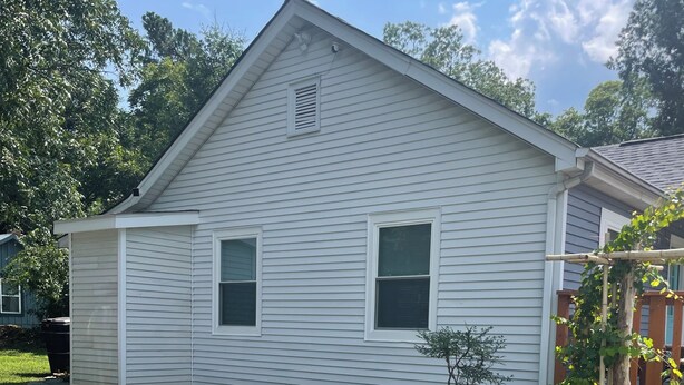 A single-story house with a front porch, a small garden, and a clear sky.