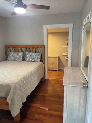A bedroom with a bed, a wooden headboard, a nightstand, a dresser, and a ceiling fan. - Cozy 2-bedroom house in delightful Roxboro with AC (Roxboro)