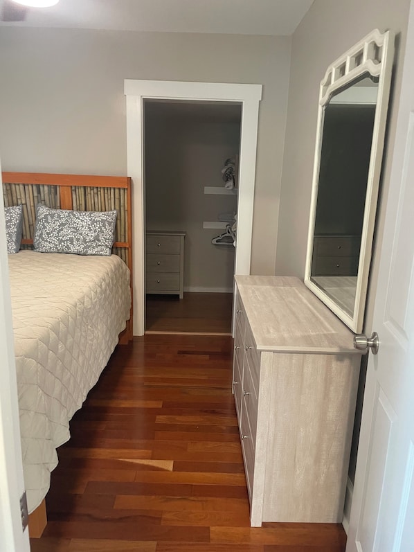 A bedroom with a bed, a dresser, a mirror, and a walk-in closet.