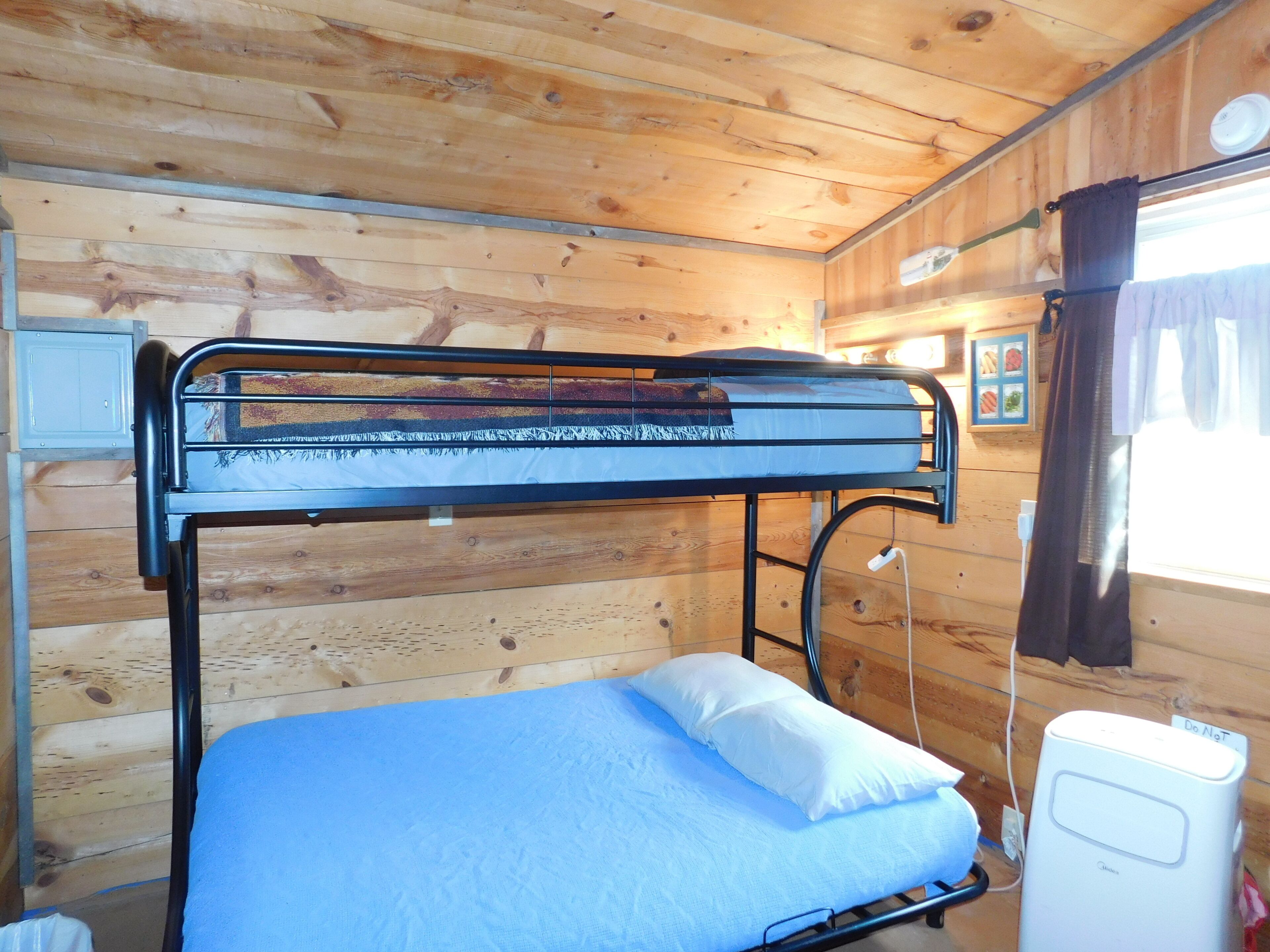 A bunk bed with a blue mattress and white pillow in a wooden cabin room.