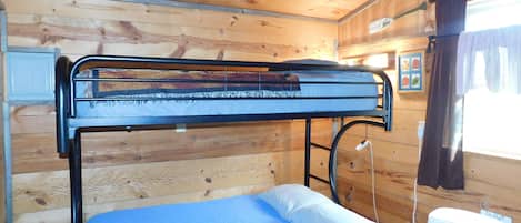 A bunk bed with a blue mattress and white pillow in a wooden cabin room.