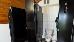 Eine öffentliche Toilette mit schwarzen Kabinen, einer weißen Toilette und einer Holzkonstruktion an der Decke.