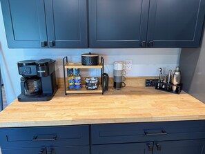 A kitchen with dark cabinets, a coffee maker, a coffee grinder, and a coffee filter holder. - Cozy 3-bedroom house located on the beautiful coast of Sedgwick, Maine. (Sedgwick)
