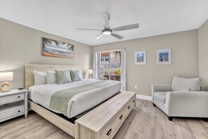 Ein Schlafzimmer mit einem Bett, Nachttischen, einem Sessel und einem Deckenventilator.