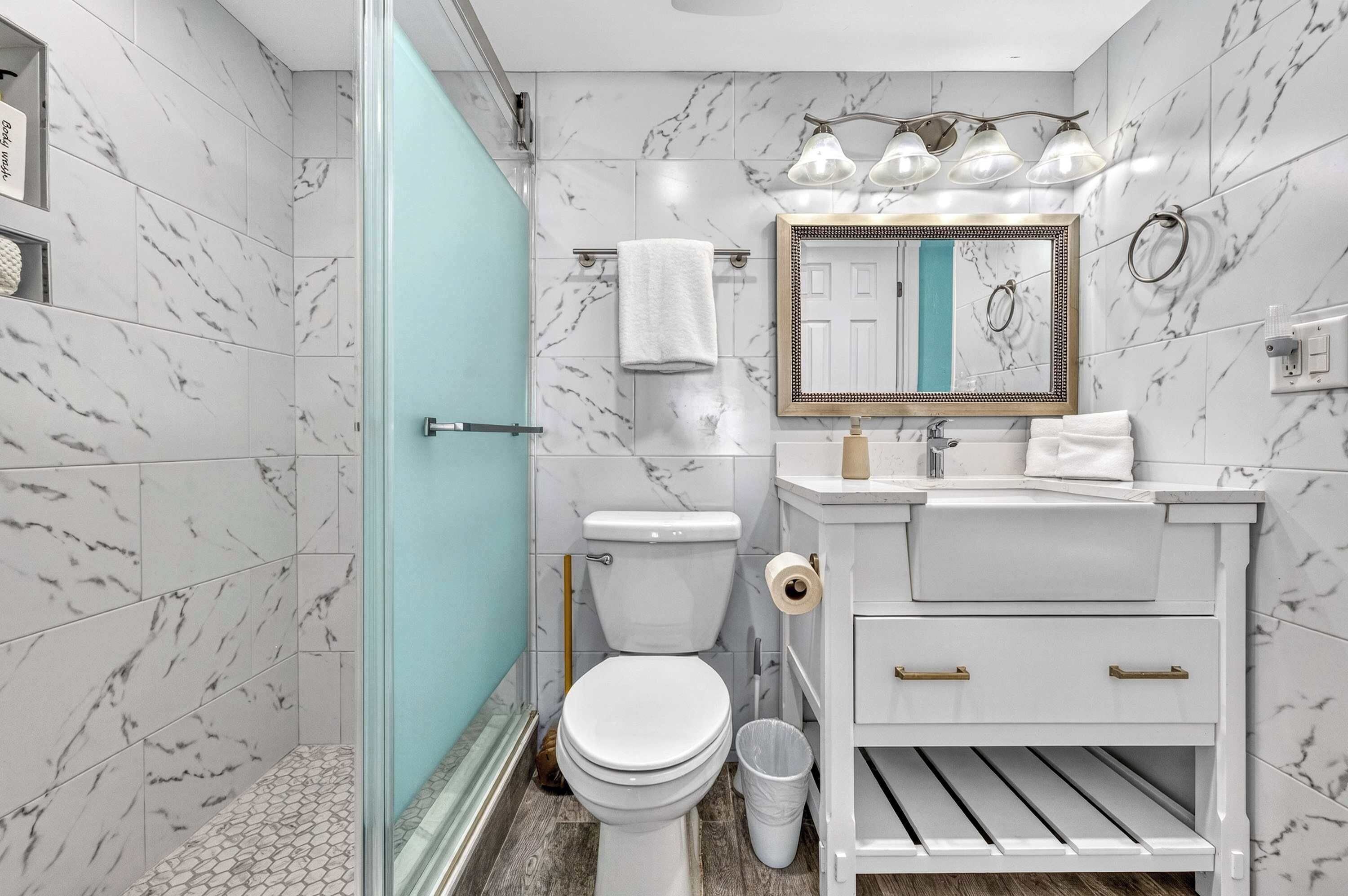 Ein Badezimmer mit Toilette, Waschbecken, Spiegel und Duschbereich.
