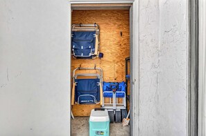 Ein schmaler Durchgang zu einem Raum mit Holzboden, zwei blauen Gepäckträgern, einer blauen Tasche und einem grünen Kühlkoffer.