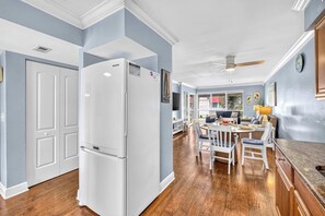 A kitchen with a white refrigerator, wooden flooring, and a dining area with a table and chairs. - Dans Florida Condos Beach Beckons at Runaway Bay (Bradenton Beach)