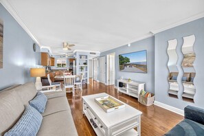 A spacious living room with a sofa, coffee table, and a television. - Dans Florida Condos Beach Beckons at Runaway Bay (Bradenton Beach)