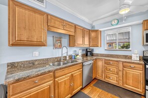 A kitchen with wooden cabinets, granite countertops, stainless steel appliances, and a window with a view. - Dans Florida Condos Beach Beckons at Runaway Bay (Bradenton Beach)