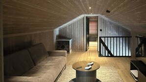 Une pièce de style « loft », avec un plafond en bois, un canapé, une table basse et un escalier menant à un niveau supérieur.