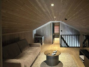 A loft-style room with a wooden ceiling, a sofa, a coffee table, and a staircase leading to an upper level. - Sunny retreat on Nesfjellet near alpine skiing (Buskerud)