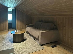A room with a wooden ceiling, a sofa, a round coffee table, and a carpeted floor. - Sunny retreat on Nesfjellet near alpine skiing (Buskerud)