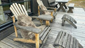 Une terrasse en bois avec des chaises Adirondack et une table de pique-nique.
