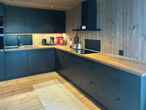 Eine moderne K üche mit dunklen Schränken, einer Holz Arbeitsplatte und einem eingebauten Herd.