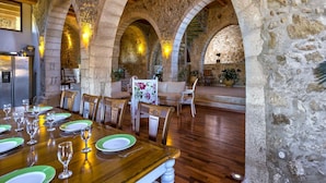 A dining area with a wooden table set for a meal, stone arches, and a stone wall. - Villa Candice With Private Pool (Rethymno)