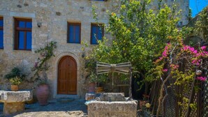 A stone building with a wooden door and windows, surrounded by potted plants and a stone fountain. - Villa Candice With Private Pool (Rethymno)