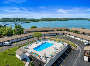 Un hôtel doté d’une piscine entourée de chaises longues et d’un parking.