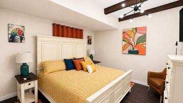 A bedroom with a bed, nightstands, a dresser, and artwork on the walls.