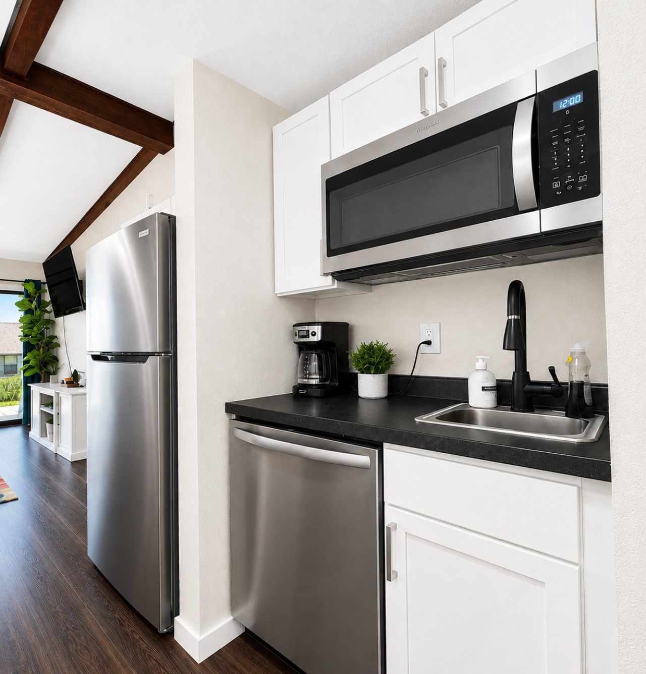 A modern kitchen with stainless steel appliances, a flat-screen TV, and a coffee maker.