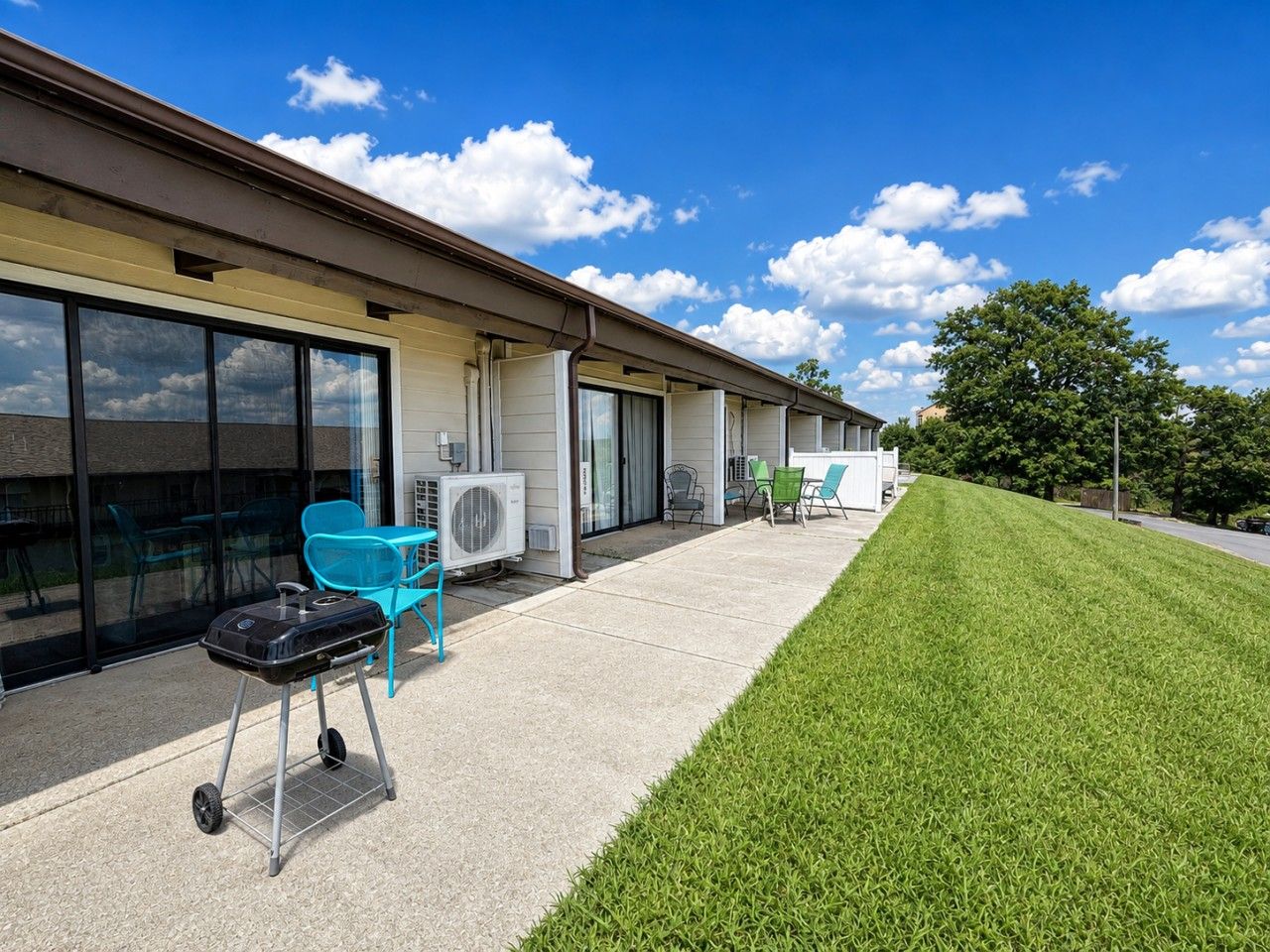 A building with a covered patio area, outdoor seating, and a well-maintained lawn.