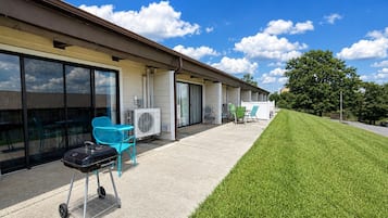 A building with a covered patio area, outdoor seating, and a well-maintained lawn.