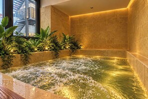 A spa area with a hot tub, tiled walls, and indoor plants. - LUMI HOTEL BEN THANH (Ho Chi Minh City)