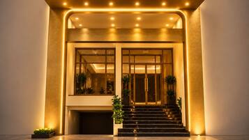 The entrance of the LUMI HOTEL with a modern design, featuring a prominent sign, a staircase, and a well-lit facade.