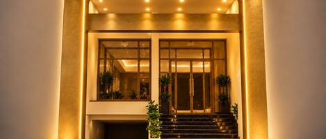 L'entrée du LUMI HOTEL présente un design moderne, avec une enseigne bien visible, un escalier et une façade bien éclairée.