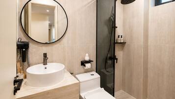 A modern bathroom with a round mirror, a sink, a toilet, and a glass-enclosed shower area.