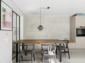 A modern dining area with a wooden table and metal chairs, a pendant light, and a kitchen with an oven. - 4 Star Holiday Home in Ronde (Ronde)