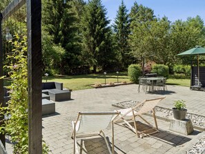Eine Terrasse im Freien mit Tisch und Stühlen, umgeben von einer Steinmauer und Grünpflanzen.