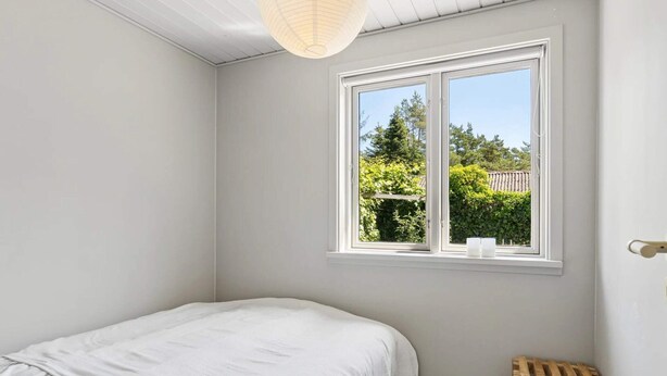 A bedroom with a single bed, a window with a view of greenery, and a wooden stool. - 4 Star Holiday Home in Ronde (Ronde)