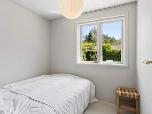 A bedroom with a single bed, a window with a view of greenery, and a wooden stool. - 4 Star Holiday Home in Ronde (Ronde)