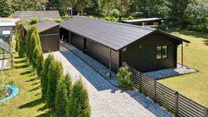 A modern building with a metal roof, surrounded by a gravel driveway and a wooden fence. - 4 Star Holiday Home in Ronde (Ronde)