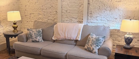 Un salon comprenant un canapé, deux tables d’appoint avec des lampes, une table basse avec des magazines et un tapis à motifs.