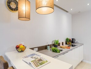 A modern kitchen with a white countertop, a fruit bowl, a magazine, and a coffee maker. - Flat on Grzybowska Street (Warsaw)