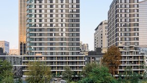 Ein modernes Hochhaus mit mehreren Stockwerken, großen Fenstern und einer geschwungenen Fassade.