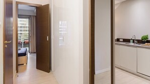 Ein modernes Hotelzimmer mit Holzboden, Blick auf einen Außenbalkon und einer Küchenzeile mit Spüle und Arbeitsfläche.