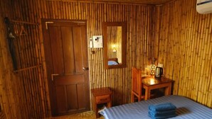 Una habitación con cama, un escritorio de madera, un espejo y una puerta.