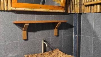 Une salle de bain avec un meuble-lavabo en bois, un grand miroir et un mur en bambou.