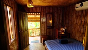 Una habitación con cama, escritorio y ventana con vistas a follaje.