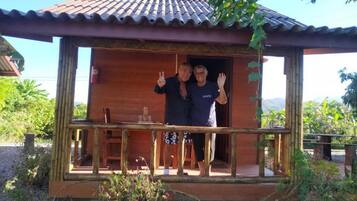 A wooden cabin with a balcony, a fire extinguisher, and a chair.