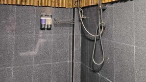 Ducha con pared de bambú, cabezal de ducha de mano y grifo empotrado.