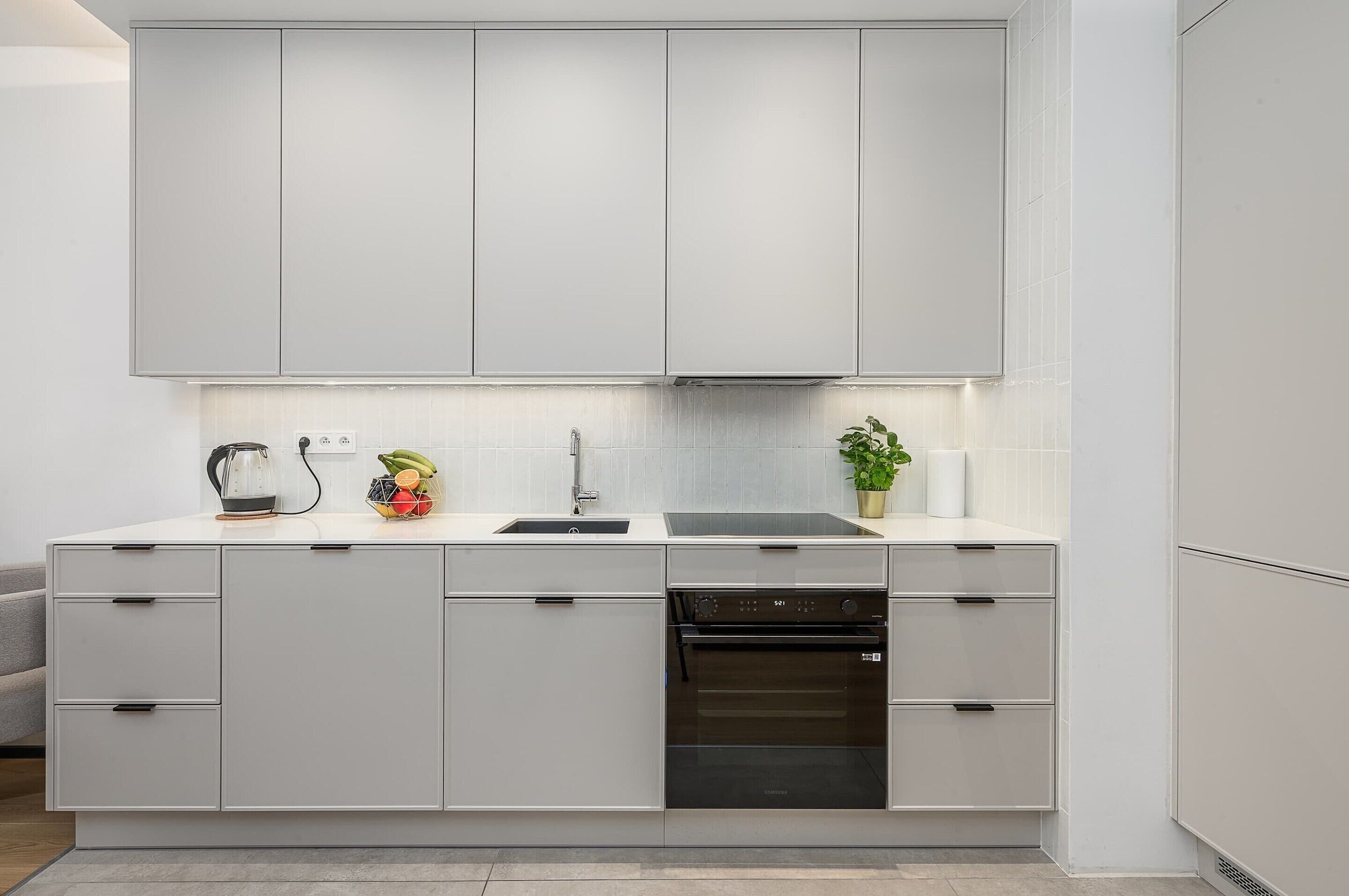 Una cocina moderna con armarios blancos, lavavajillas integrado y horno Samsung.