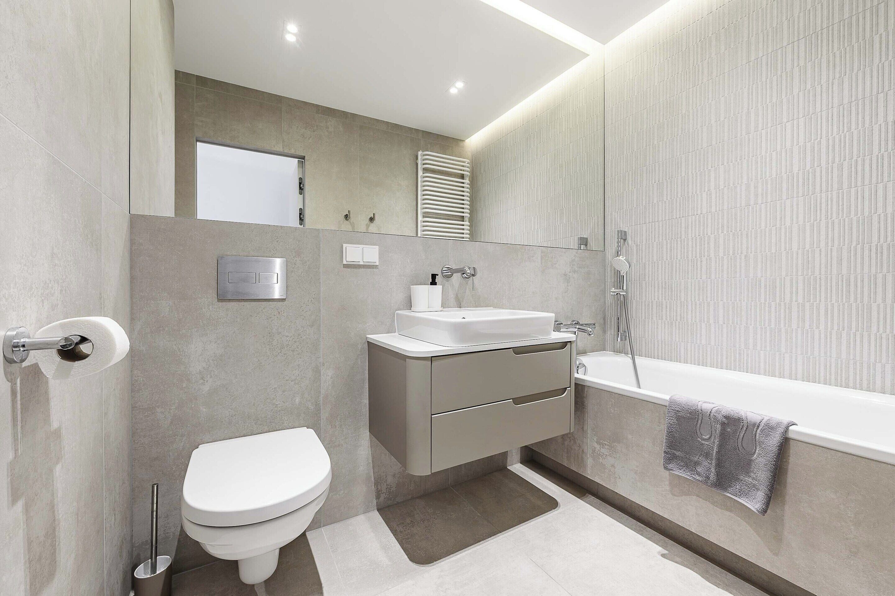 Een moderne badkamer met toilet, wastafel en bad.