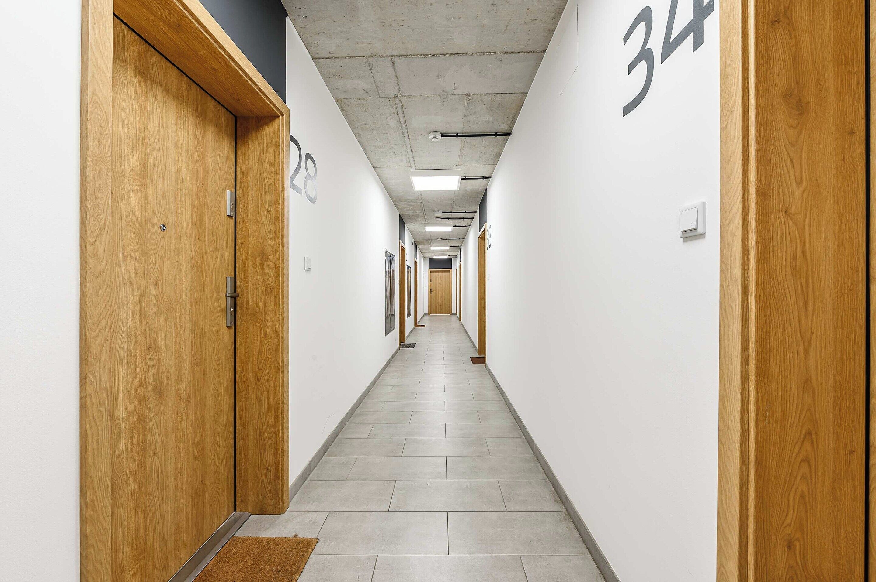 Un pasillo con puertas de madera, con los números 28 y 34, que dan a varias habitaciones.